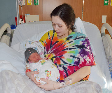 Sweet young mom gazes down on newborn daughter