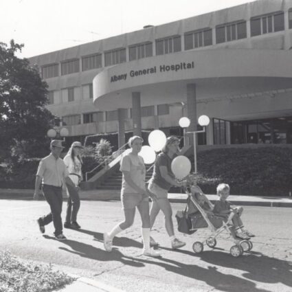A family walking in front of the newer Albany General Hospital building, circa 1970s.