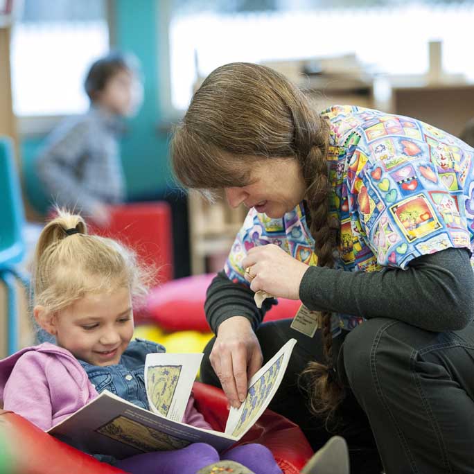Local woman reading a picture book with a small child.