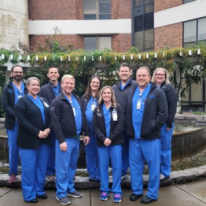 Nine people wearing blue scrubs