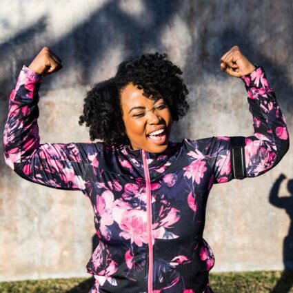 Smiling woman raising her arms over her head invictory.