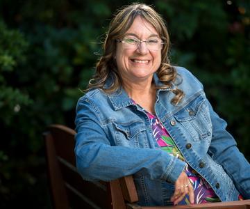 Shelli Baxter of Sweet Home sitting sideways on a bench smiling for photo shoot to highlight her diabetes journey.