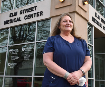 Certified medical assistant standing outside the clinic where she works