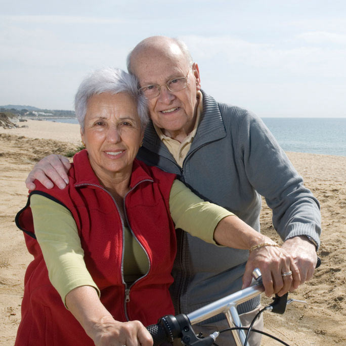 Couple with bike and beach in background