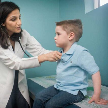 Doctor using a stethoscope on little boy.