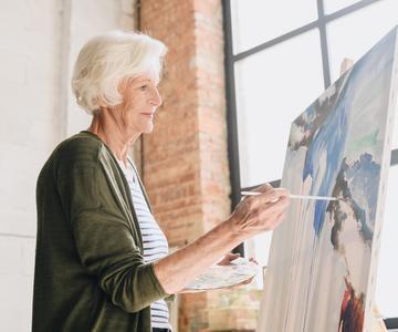 Senior woman painting at an easel.