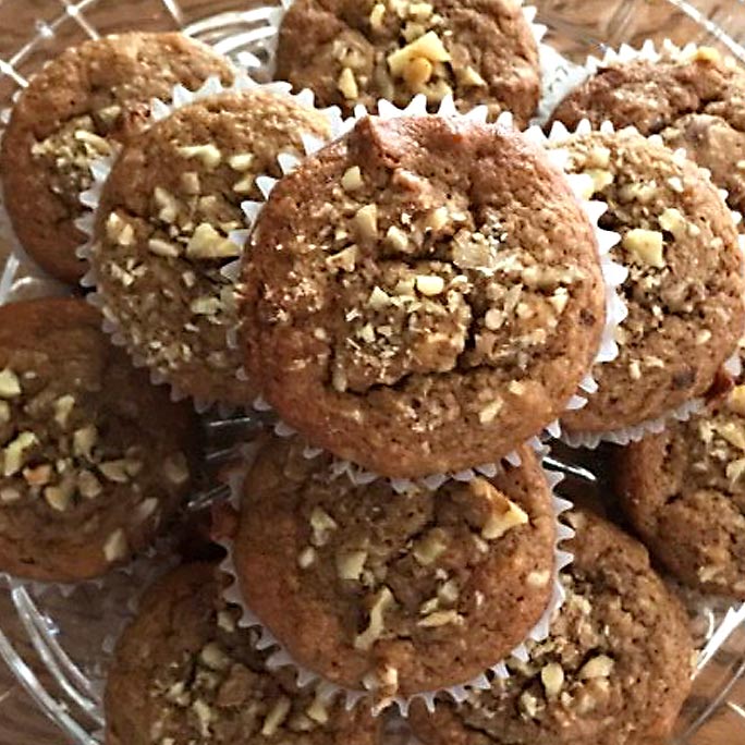 Plate of banana muffins with nuts on top.