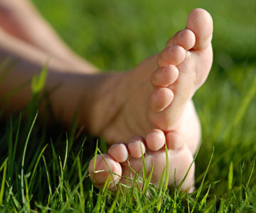 Bare feet laying in green grass.