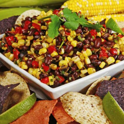 Square plate of bean salad with beans and corn, garnished with cilantro.