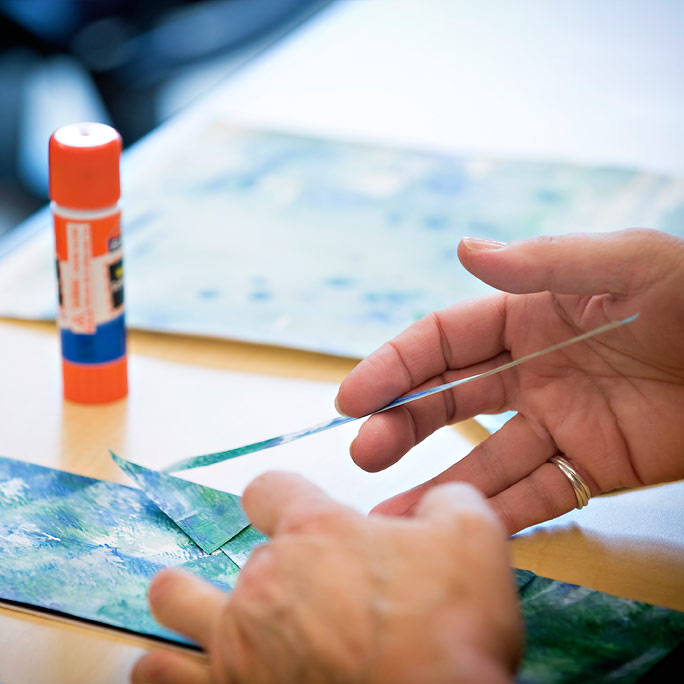 Close up of a woman's hands as she creates a colorful project at an ArtsCare event.