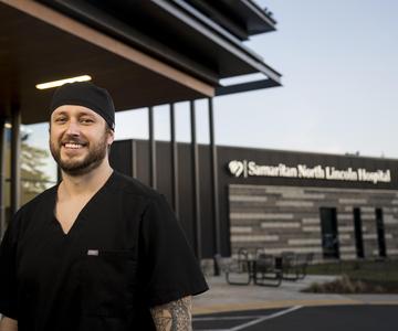 Cameron Vasquez standing in front of Samaritan North Lincoln Hospital's entrance.