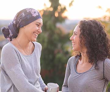 two women smiling outdoors for cancer support
