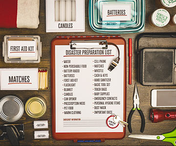 A list for an emergency tool kit along with various supplies on a table.