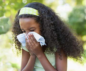 Young girl sneezing into a handkerchief