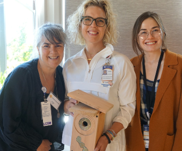 three women stand with a bird box after award ceremony.