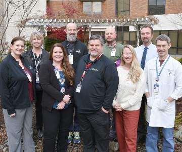 Four women and five men stand in front in a healing garden.