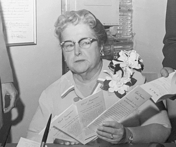 Woman looking wearing glasses looking over brochures.