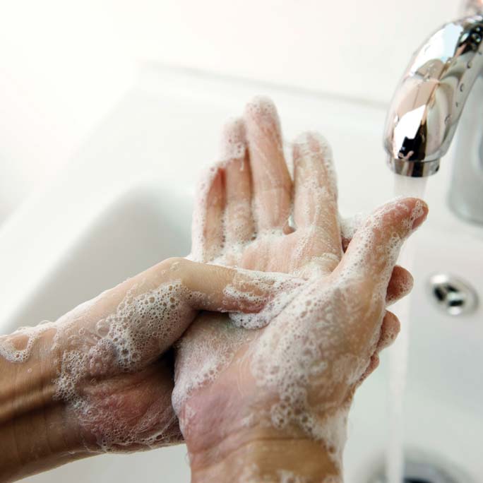Handwashing under faucet with lathered soap