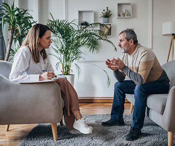 Older man talking with female psychologist in a counseling session.