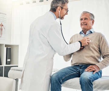 Physicians listens to patient's chest with stethoscope.