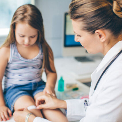 Clinician putting bandaid on a little child's knee.
