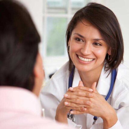 Person with stethoscope smiles at other.