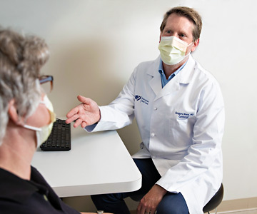 Dr. Gregory Wood talks with a heart patient in his office.