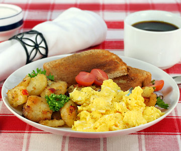 A plate of scrambled eggs, hashbrowns and toast with coffee.