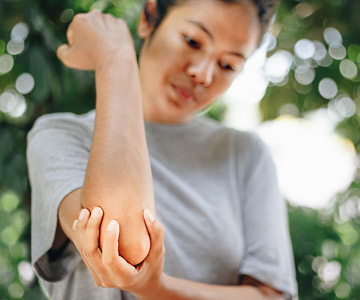 Person grabbing their elbow that is in pain.