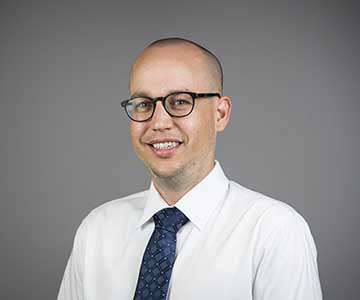 Man wearing glasses in a white shirt and tie.