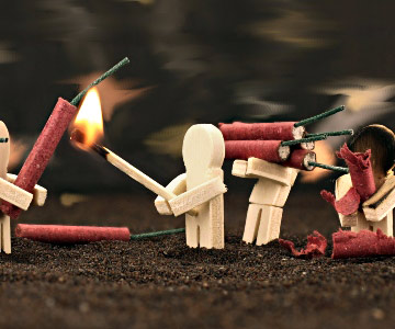 A stick figure lights fireworks with a match. A common cause of emergency room visits on the Fourth of July are fireworks.