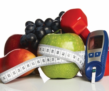 apple with a tape measure around it with other fruit and a Glucose monitor
