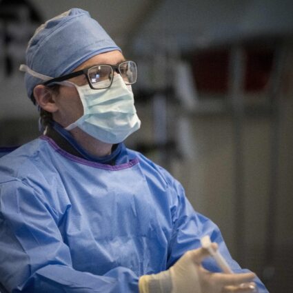 Surgeon looks at screen reflected in their eyeglasses.