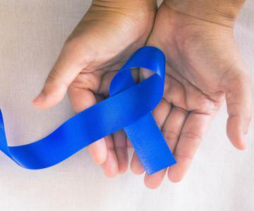 Hands holding deep blue ribbon on white fabric with copy space.