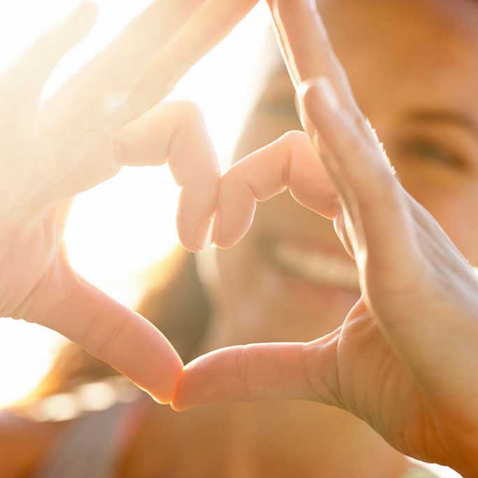 Hands held in shape of heart in front of smiling face