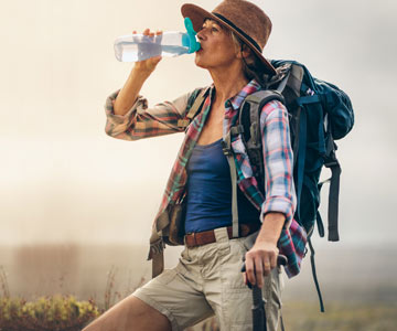 Woman wearing backpack drinking water