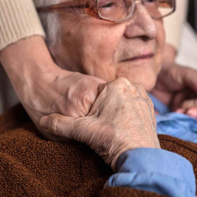 Older male holding hand of a younger person on his shoulder
