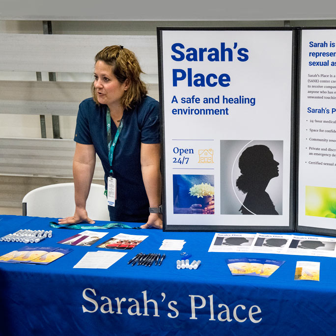 A volunteer sharing educational pamphlets about Sarah's Place at a local event.