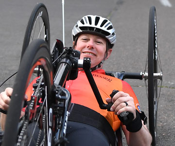 Close up of Jeremy hand-pedaling his bike on a street.