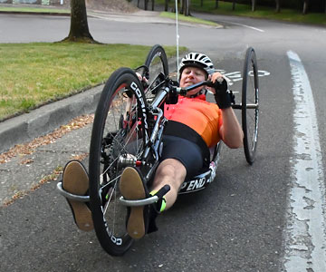 Jeremy hand-pedaling his bike down a street.