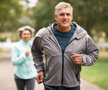 Man jogging in foreground, woman jogging out of focus in background