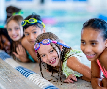 A group of happy kids at the edge of a swimming pool.
