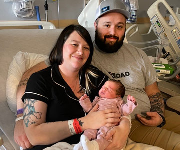 Woman, man and newborn in hospital bed.