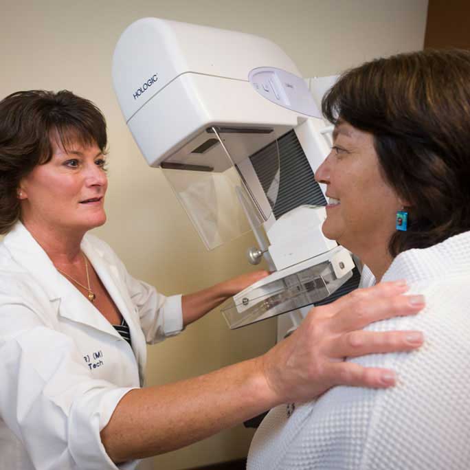 Provider getting a patient ready for a mammogram.