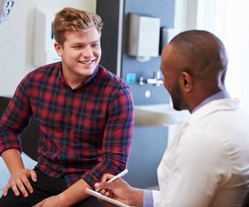 Man in flannel shirt talks with doctor in white coat
