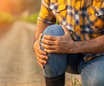 Man kneeling down holding his knee in pain.