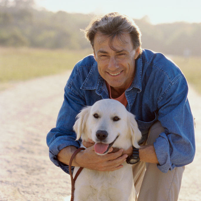 Adult smiling and hugging his dog.