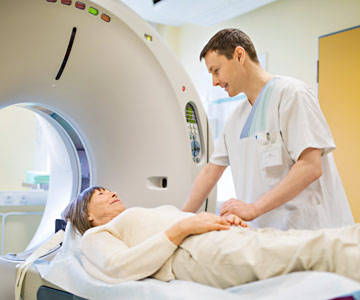 An MRI tech talks to woman before MRI scan.