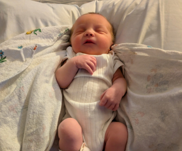 Baby Nora sleeps on a white blanket.