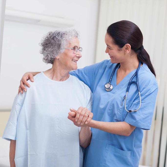 Female doctor assisting an elderly woman patient stand